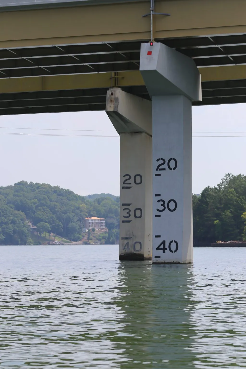 Bridge piers stand in water, with painted clearance markings on one pillar.